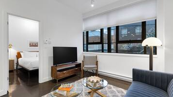 A modern living room with a bed, TV, and seating area.