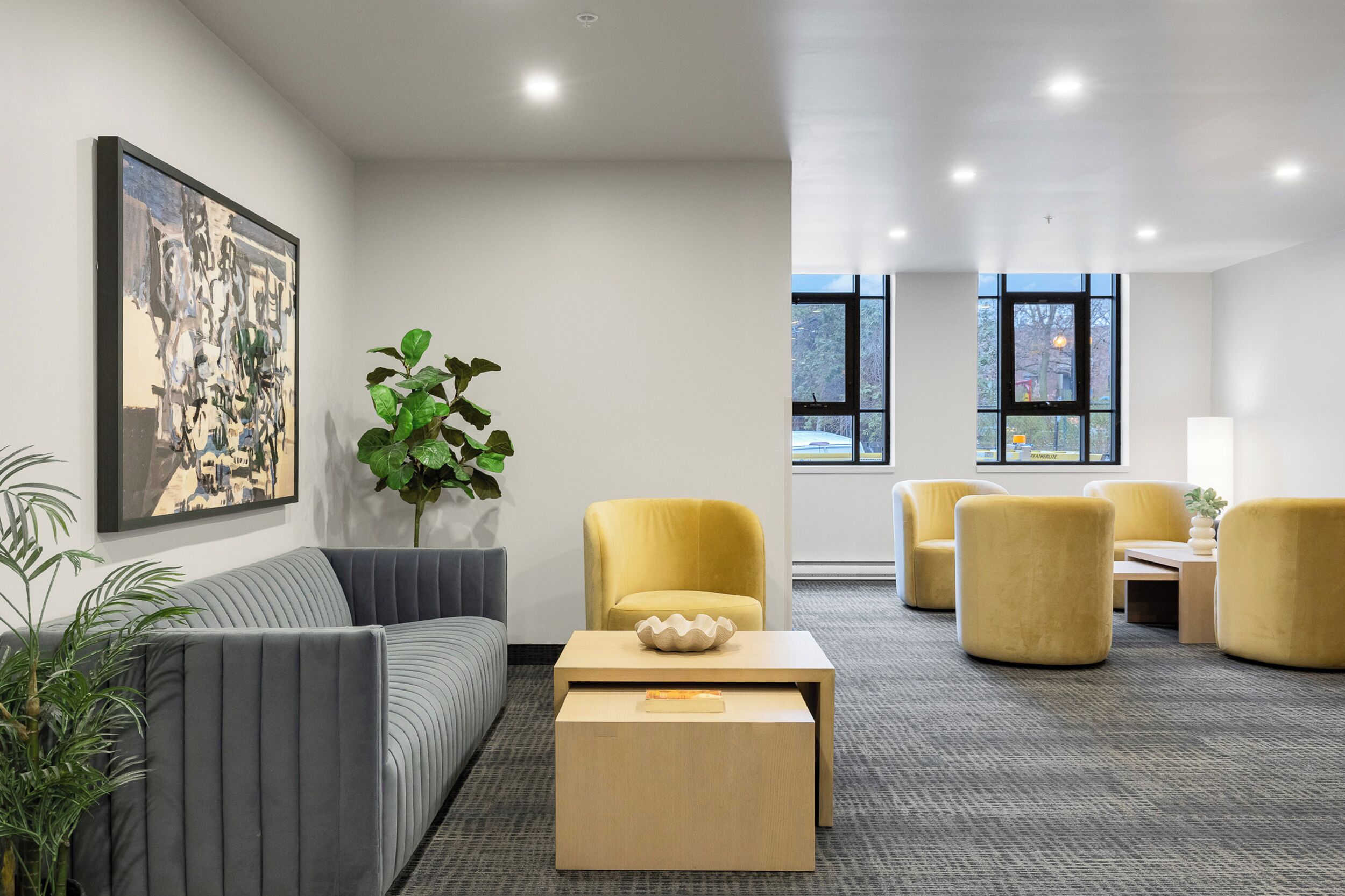 A modern interior with a sofa, yellow chairs, a coffee table, and a large window.
