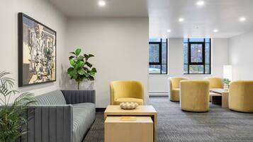 A modern interior with a sofa, yellow chairs, a coffee table, and a large window.