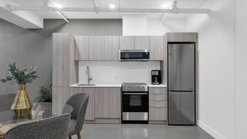 Una cocina moderna con armarios de madera clara, electrodomésticos de acero inoxidable y una mesa de comedor de vidrio con sillas.
