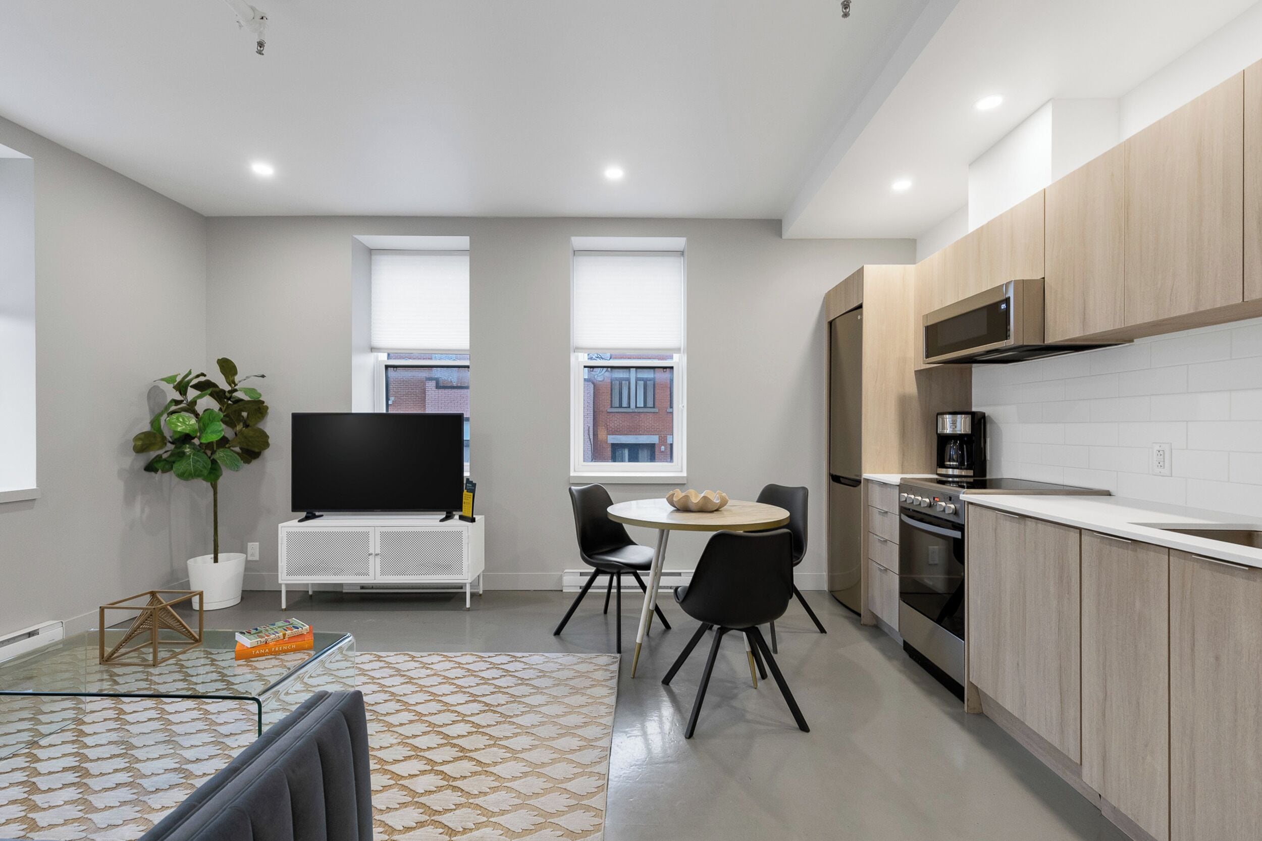A modern kitchen with a microwave, oven, and a dining area with a table and chairs.