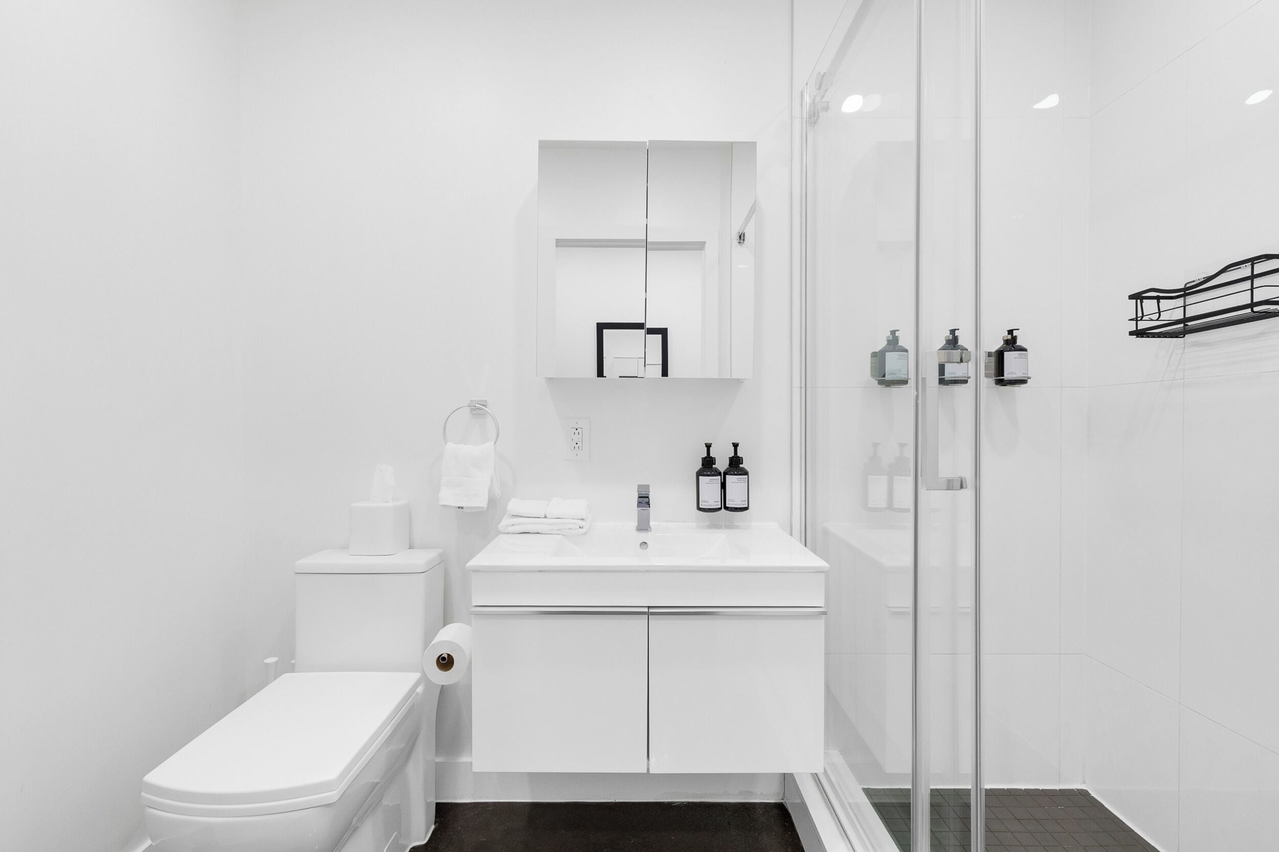 Un baño moderno con inodoro, lavamanos y cabina de ducha de vidrio.