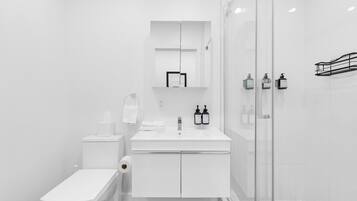 Un baño moderno con inodoro, lavamanos y cabina de ducha de vidrio.