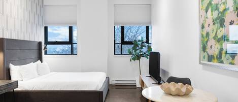 Um quarto moderno com uma cama, uma escrivaninha, uma cadeira e uma janela grande.