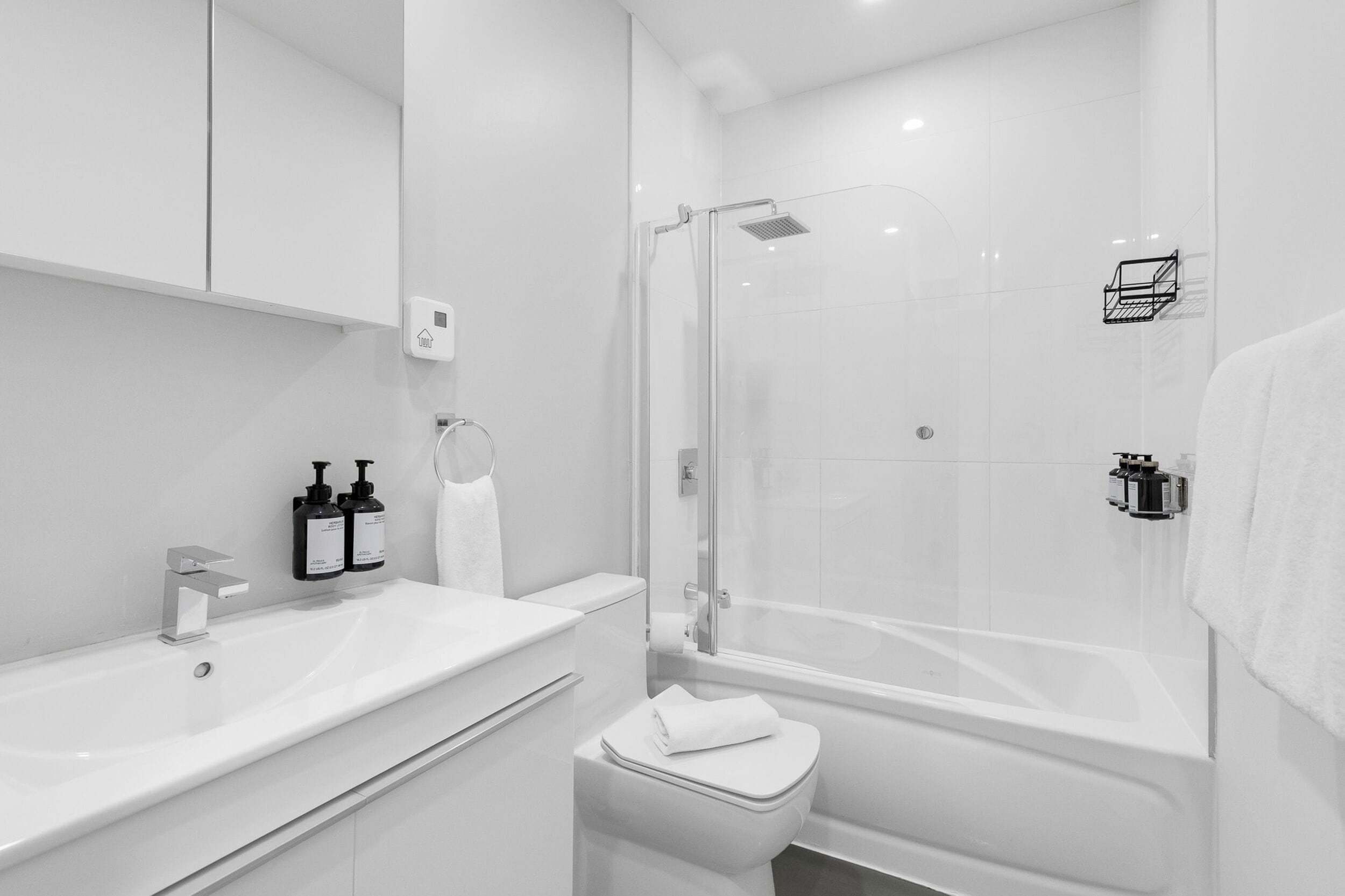 Ein modernes Badezimmer mit einer gläsernen Dusche, einem weißen Waschbecken und einer Toilette.