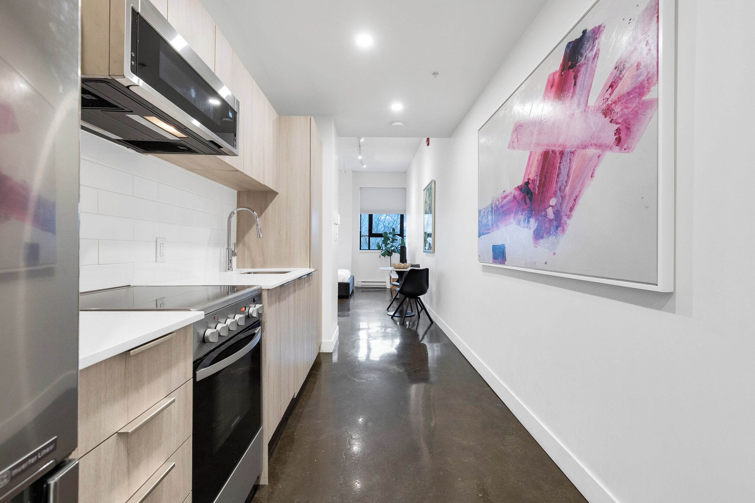A modern kitchen with stainless steel appliances, a wooden countertop, and a dining area with a table and chairs.