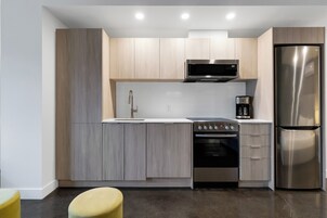 Une cuisine moderne avec des meubles en bois clair, des appareils en acier inoxydable, un four encastré et une machine à café.