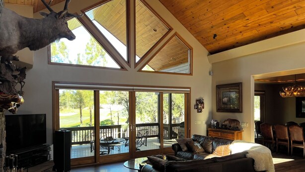 A spacious living room with a large fireplace, a leather sofa, and a dining area with a chandelier.