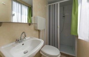 A bathroom with a white sink, a toilet, and a shower with a striped glass door. - 2 bedroom awesome (sta)caravan in Labin (Labin)