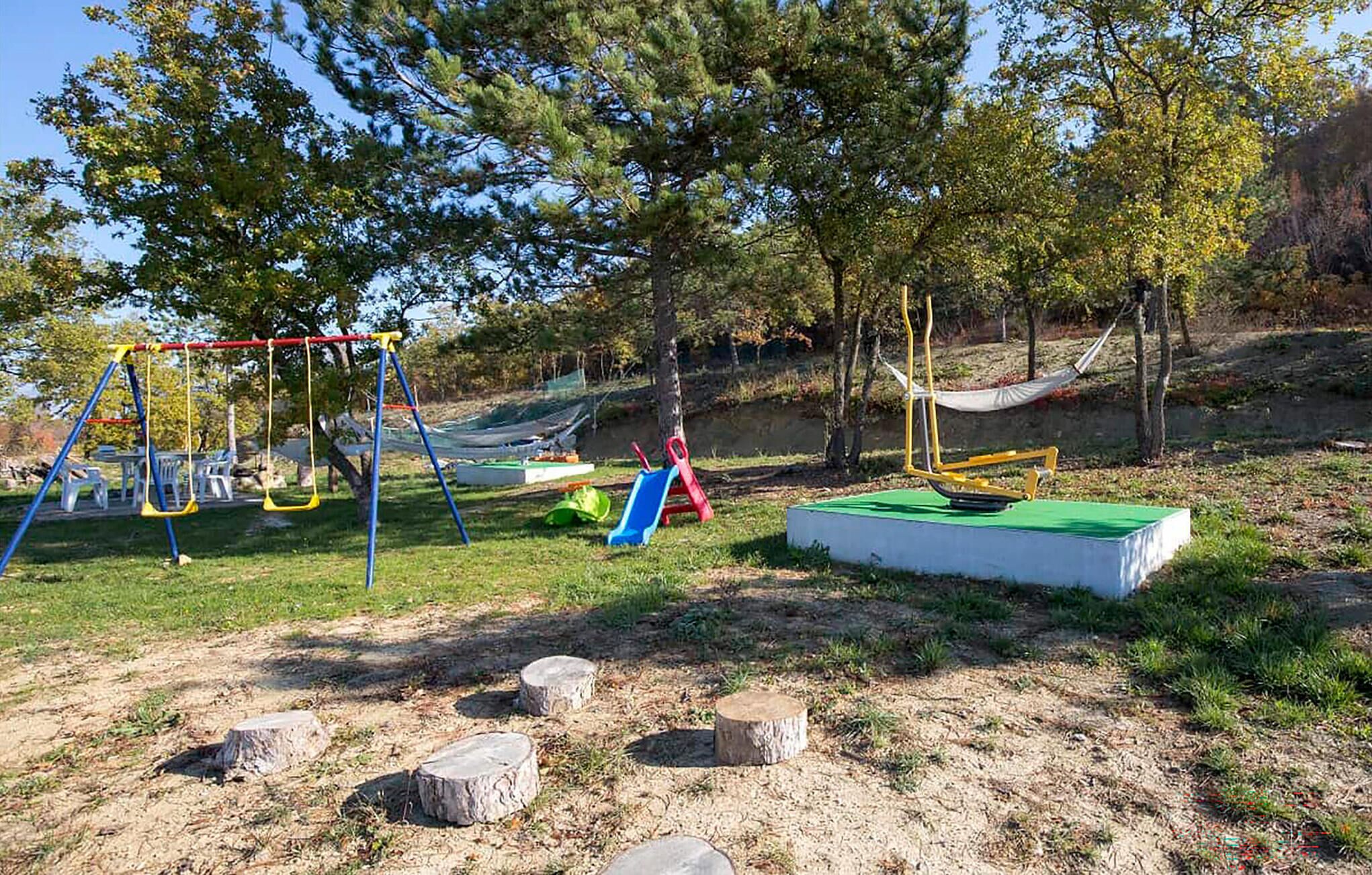 Un parque infantil con columpios, toboganes y una hamaca.