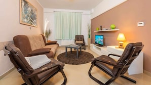 A living room with a brown leather sofa, two leather chairs, a coffee table, a television, and a lamp. - 1 bedroom cozy apartment in Labin (Labin)