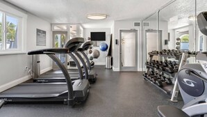 A fitness center with treadmills, a stationary bike, and a wall of dumbbells. - Cozy King Suite Near Bayshore | Pool & Gym (Tampa)