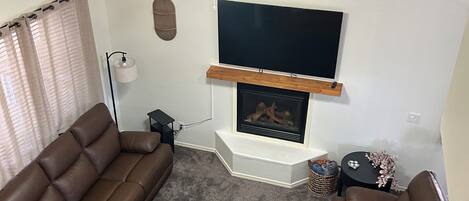 A living room with a fireplace, two sofas, a coffee table, and a ceiling fan.