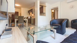 A modern living room with a glass coffee table, a leather sofa, and a dining area with a wooden table and chairs. - 3 bedroom nice apartment in Pula (Pula)