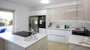 A modern kitchen with white cabinets, a built-in oven, a stainless steel refrigerator, and a marble countertop. - Stunning apartment in Pula (Pula)