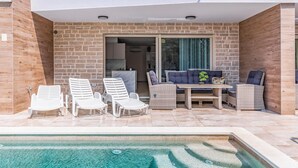 A poolside area with lounge chairs, a table, and a sofa. - Stunning apartment in Pula (Pula)