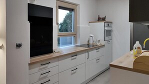 A modern kitchen with white cabinets, a wooden countertop, a window, and built-in appliances. - 3 bedroom beautiful apartment in Barban (Barban)