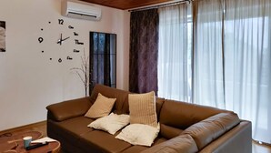 A living room with a brown leather sofa, two white pillows, a small wooden coffee table, and a wall clock. - 3 bedroom beautiful apartment in Barban (Barban)