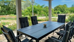Um pátio ao ar livre com uma mesa retangular e quatro cadeiras.