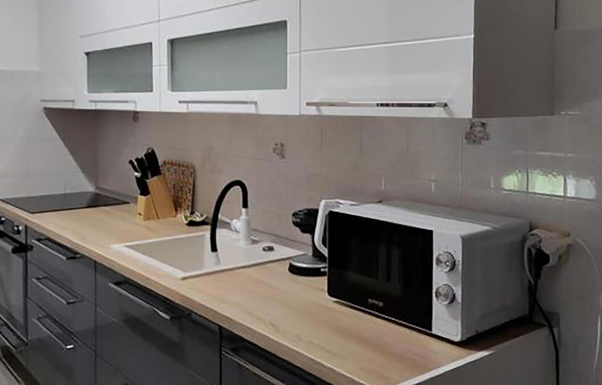 A modern kitchen with a microwave, sink, and knife block.