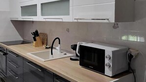 Cozinha moderna com micro-ondas, pia e porta-facas.