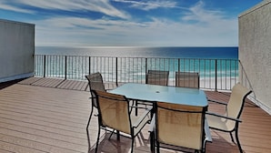 Een balkon met een tafel en stoelen met uitzicht op het strand.