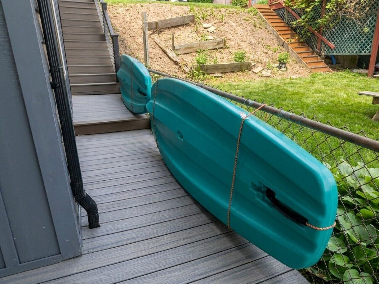 A wooden deck with a kayak tied to a railing.