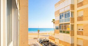 Blick vom Balkon auf einen Strand bei strahlendem Himmel.