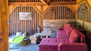Un intérieur chaleureux avec un plafond en bois, un canapé confortable, une petite table et une chaise.