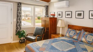 A bedroom with a large bed, a chair, a nightstand, a lamp, a potted plant, and a window with curtains. - Luxe Haven Room, with a Private Bathroom with a Separate Entrance from the House (Waynesboro)