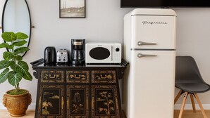 A kitchen with a white refrigerator, a coffee maker, a toaster, and a microwave on a black cabinet. There is a potted plant and a framed picture on the wall. - Luxe Haven Room, with a Private Bathroom with a Separate Entrance from the House (Waynesboro)