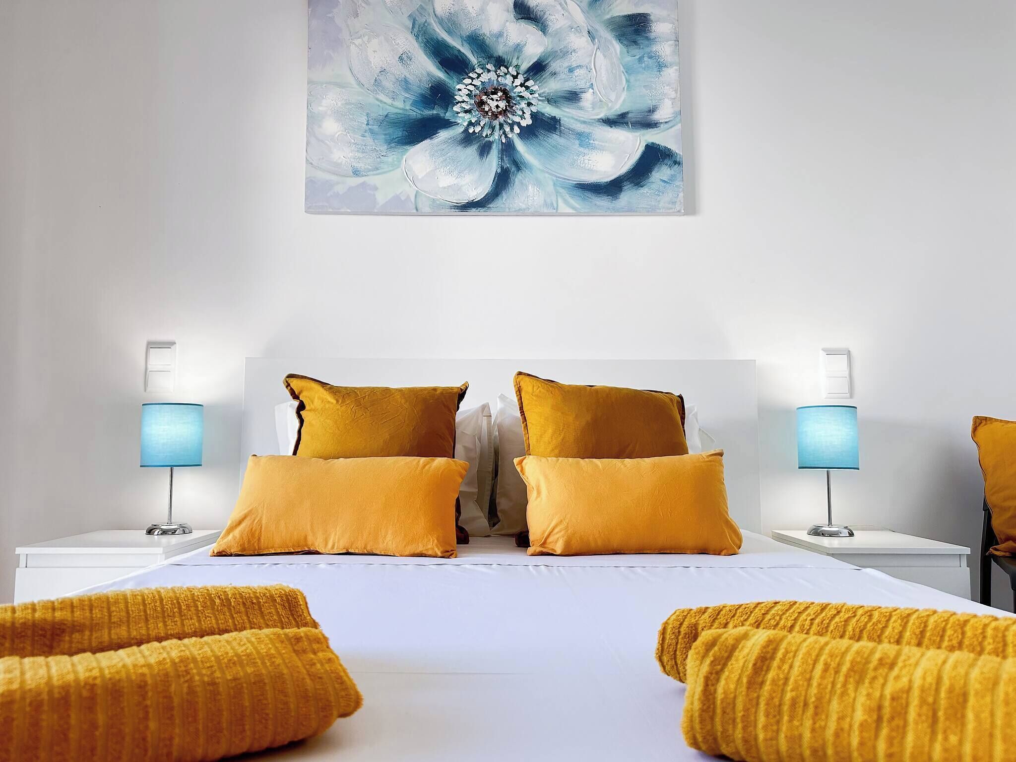 Een hotelkamer met een groot bed, twee bedlampen en een schilderij aan de muur.