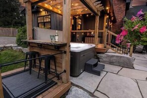 Un espace extérieur aménagé avec un jacuzzi, une terrasse en bois et un patio en pierre.