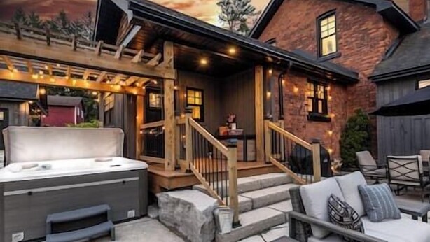 Un patio exterior acogedor con un jacuzzi, escalones de piedra y barandillas de madera.