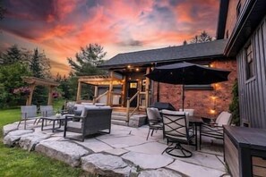 Une terrasse extérieure avec un sol en pierre, du mobilier d’extérieur et un espace salon abrité.