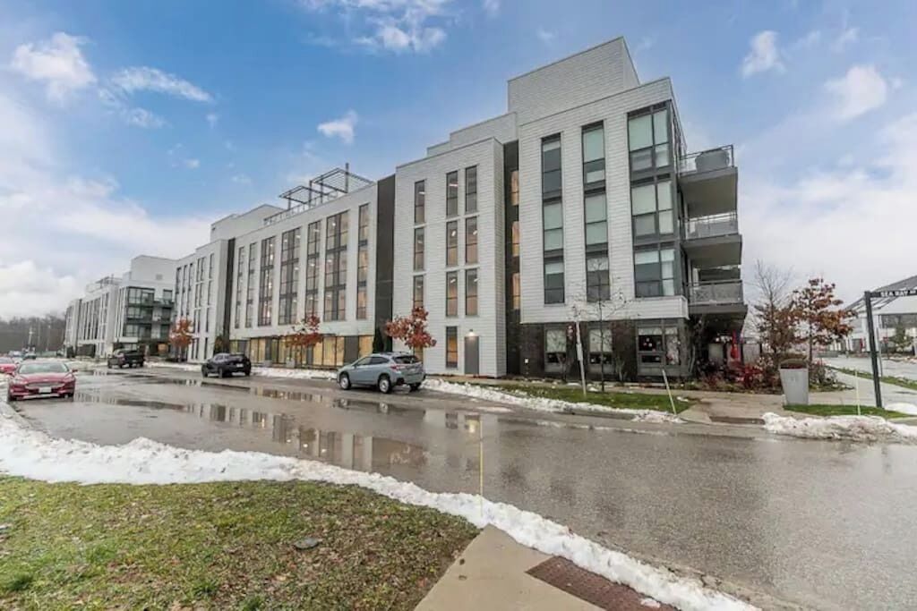 A modern multi-story building with a mix of residential and commercial spaces, featuring large windows and a flat roof.