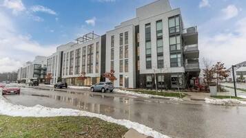 A modern multi-story building with a mix of residential and commercial spaces, featuring large windows and a flat roof.