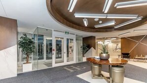 Un hall d’entrée moderne avec une table ronde en bois, des plantes en pot et une porte d’entrée en verre.