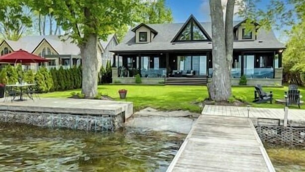 Ein modernes Haus mit einer großen Terrasse, einem Teich und einem gepflegten Rasen.