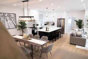 Een moderne keuken met een centraal eiland, barkrukken en hanglampen.