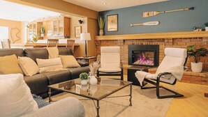 Una sala de estar con chimenea, un sofá, una mesa de centro y una zona de comedor al fondo.