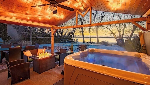 Un espacio al aire libre techado con un jacuzzi, mobiliario de mimbre y un ventilador de techo.