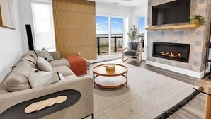 Una sala de estar moderna con un sofá, una chimenea y un ventanal grande.