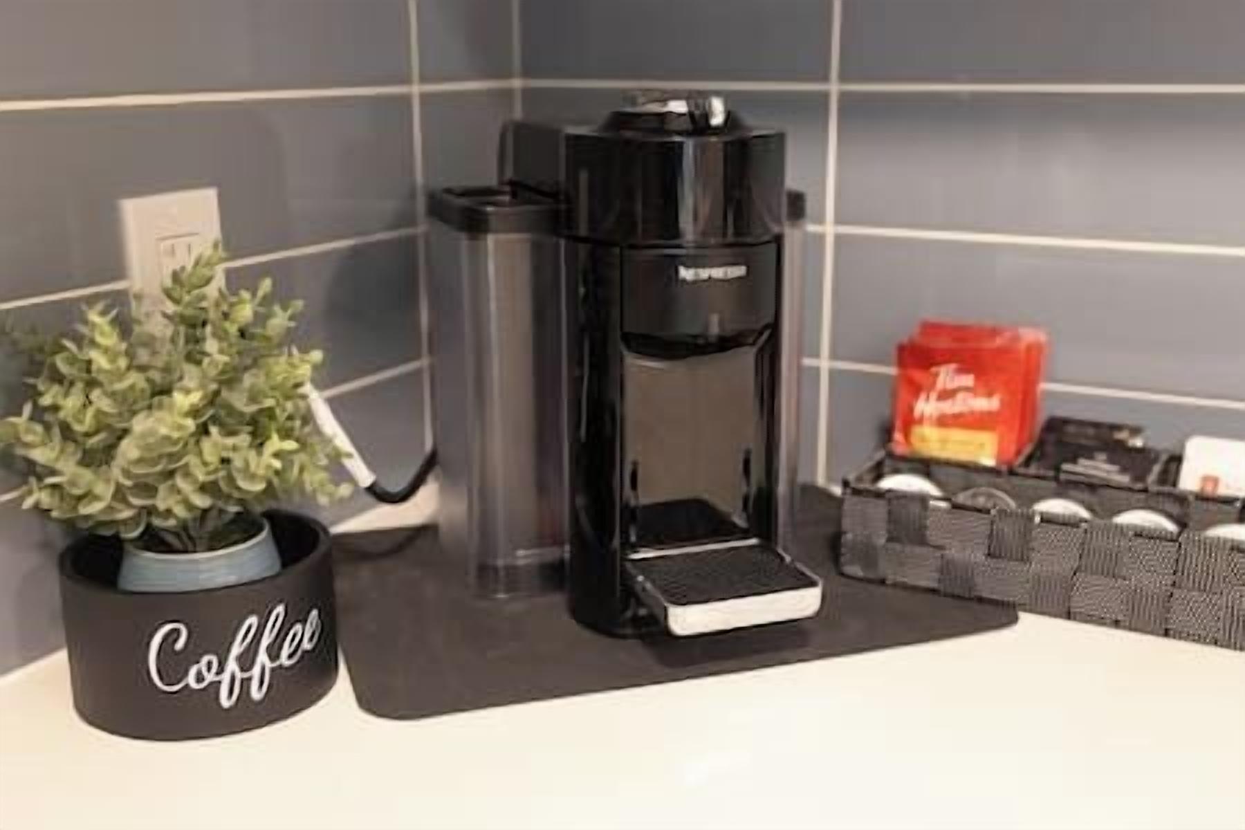 Een koffiezetapparaat op een aanrecht, met een koffiemok met de tekst 'Coffee' en een pakje koffiecups.