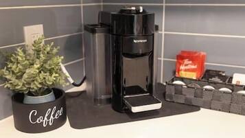 Een koffiezetapparaat op een aanrecht, met een koffiemok met de tekst 'Coffee' en een pakje koffiecups.