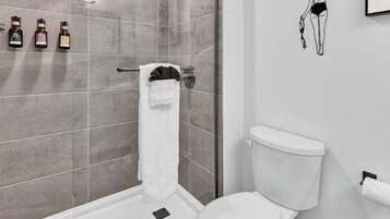 A modern bathroom with a glass shower enclosure, a white toilet, and a towel rack.