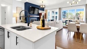 Une cuisine moderne dotée d’un grand îlot central, de meubles blancs et d’un coin repas avec une table et des chaises.