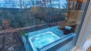 A hot tub on a patio with a view of a forested area.