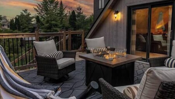 Un patio al aire libre con una chimenea, mobiliario de mimbre y vistas del paisaje circundante.