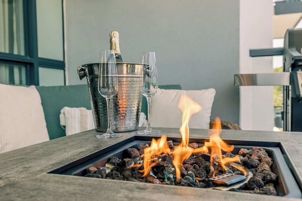 Una chimenea con una botella de champán y copas sobre una mesa.